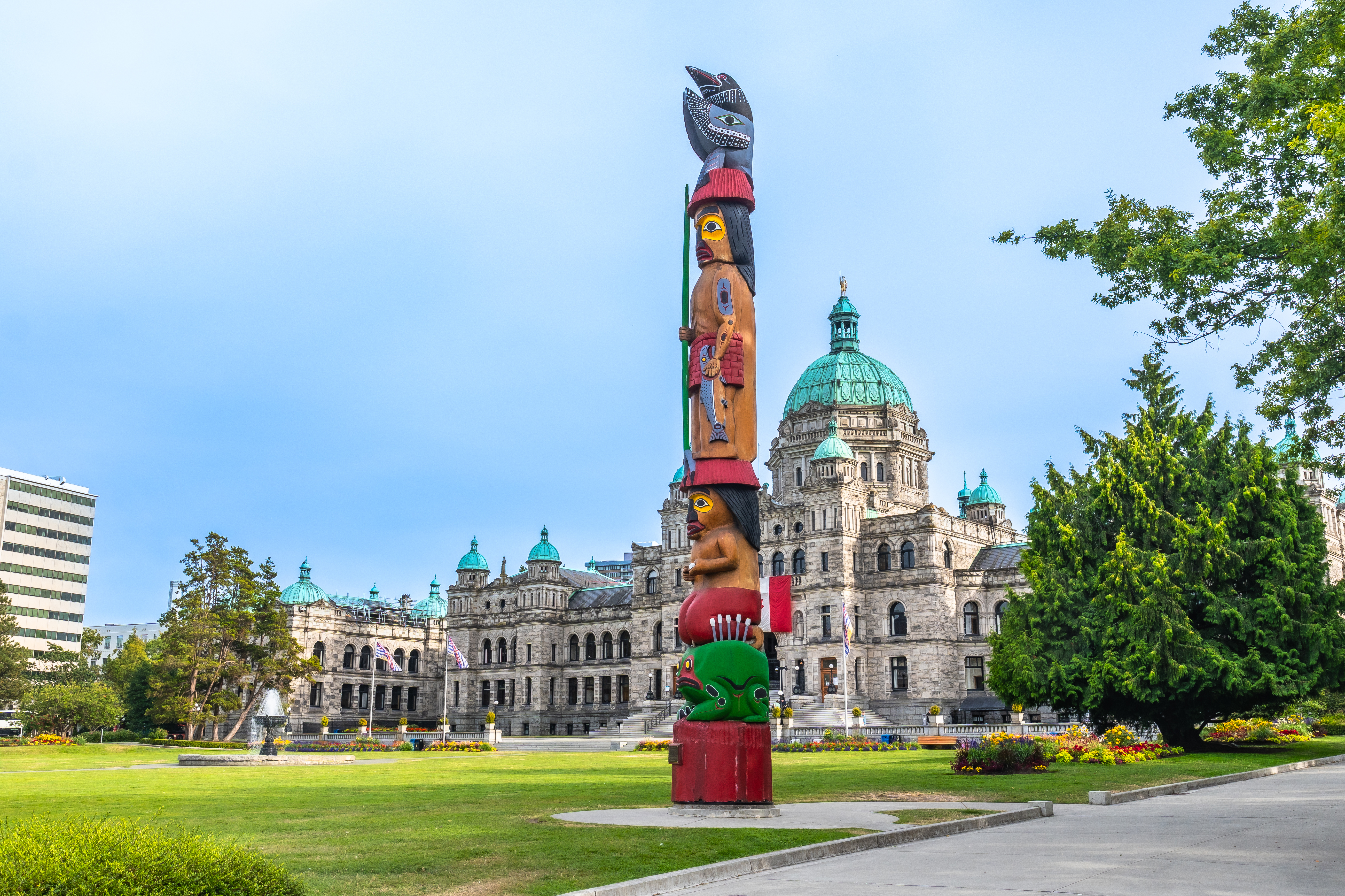 Totem pole standing tall in front of parliament buildings in victoria, british columbia