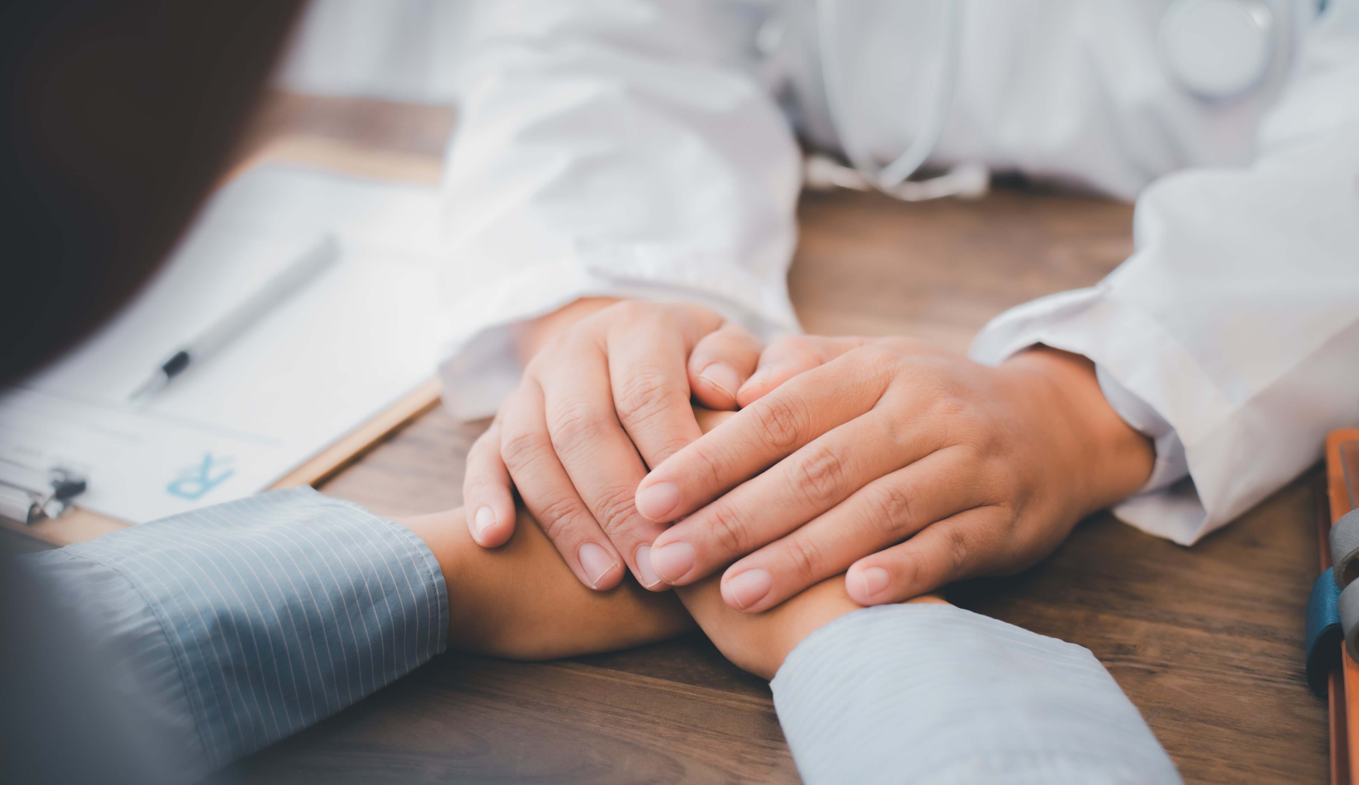 Close up of the psychiatrist's hand holding the patient's hand.